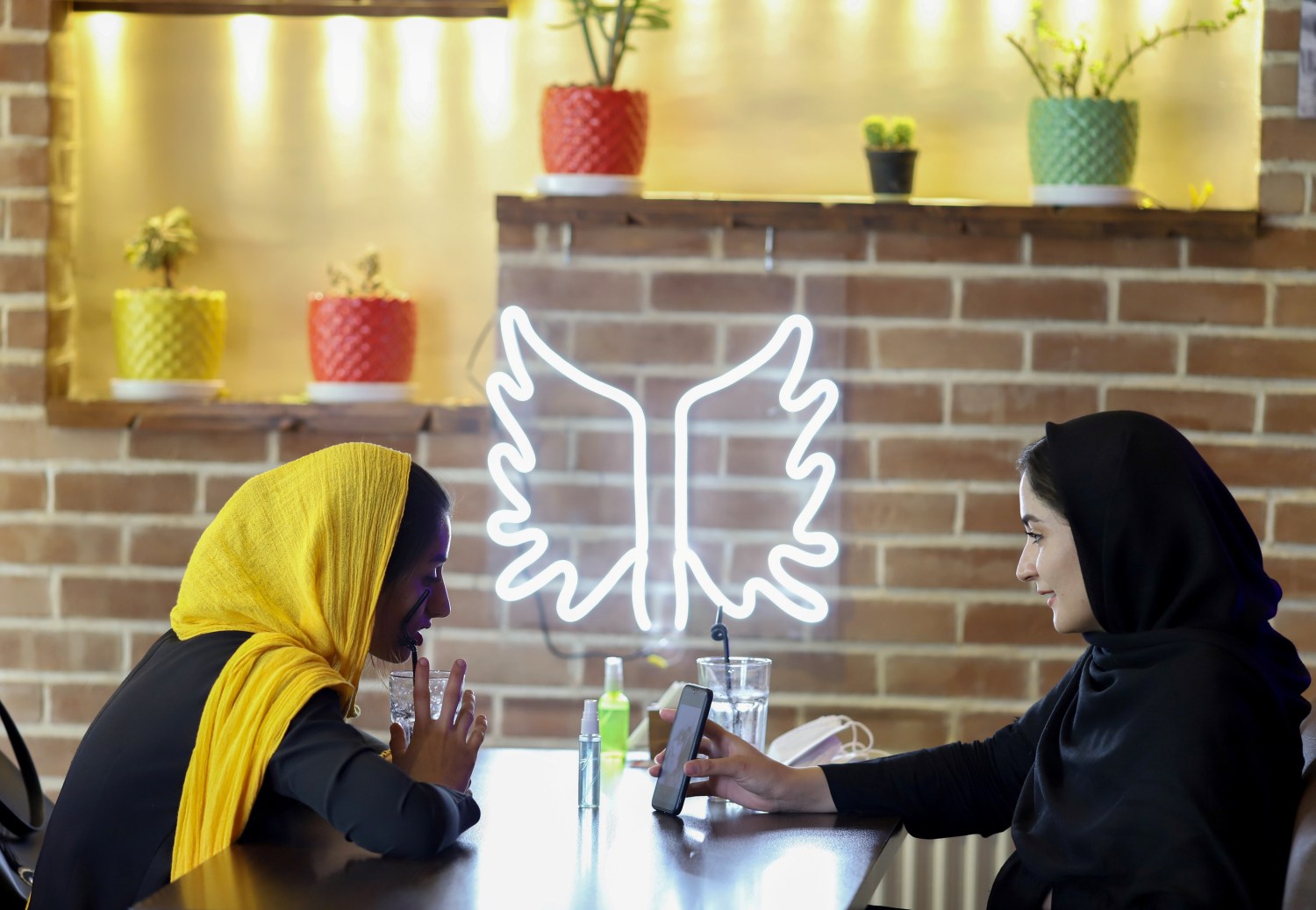 Iranian women sit in a cafe after the launching of the "Hamdam" dating app, in Tehran, Iran, July 17, 2021. Picture taken July 17, 2021. Majid Asgaripour/WANA (West Asia News Agency) via REUTERS ATTENTION EDITORS - THIS IMAGE HAS BEEN SUPPLIED BY A THIRD PARTY.