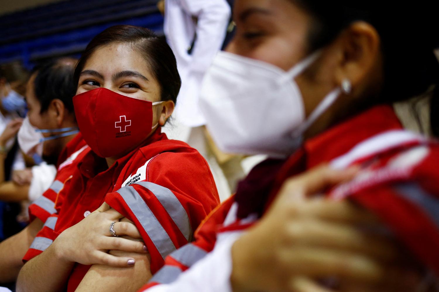 Mexican Red Cross paramedics press on her arm after receiving a booster shot of the AstraZeneca coronavirus disease (COVID-19) vaccine, in Ciudad Juarez, Mexico January 6, 2022. REUTERS/Jose Luis Gonzalez