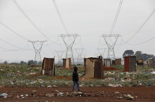 A boy walks past makeshift toilets erected beneath electricity pylons, ahead of local government elections in Evaton, south of Johannesburg, South Africa, October 27, 2021. REUTERS/Siphiwe Sibeko