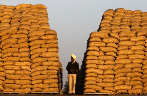 A watchman stands next to heaps of sacks filled with paddy at a wholesale grain market in the northern Indian city of Chandigarh November 15, 2014. India's inflation dropped to a new multi-year low in October, helped by slower annual rises in food and fuel prices, intensifying pressure on the central bank to cut interest rates to encourage spending and investment needed to boost growth. REUTERS/Ajay Verma (INDIA - Tags: BUSINESS COMMODITIES)