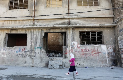 A girl walks near a building destroyed during past fighting with Islamic State militants, in the old city of Mosul, Iraq February 1, 2022. REUTERS/Khalid al-Mousily