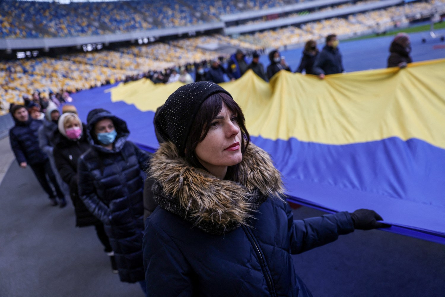 Residents carry Ukrainian national flag as they gather in the Olympic Stadium to mark the Unity Day, the day Western intelligence agencies allegedly said they'd be invaded by Russia, in Kyiv, Ukraine, February 16, 2022. REUTERS/Umit Bektas     TPX IMAGES OF THE DAY