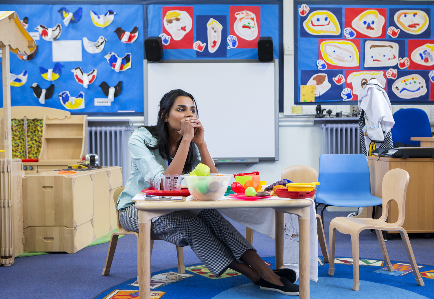 Teacher sitting in an empty classroom with nervous look on her face