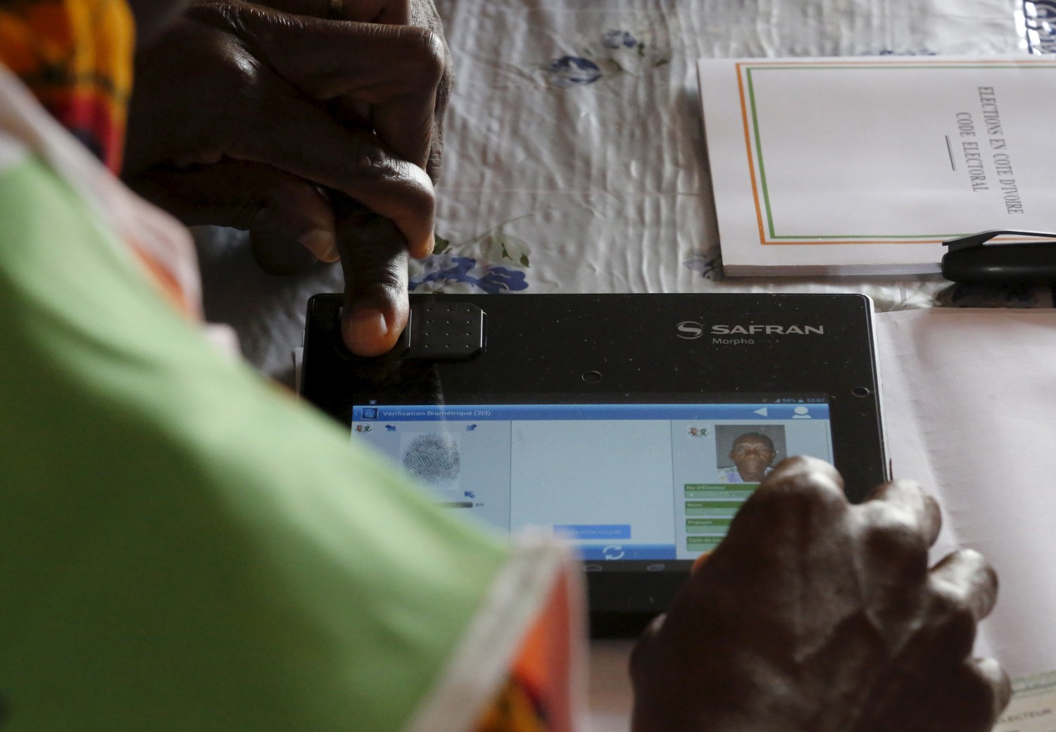 An election official checks the biometric identification information of a voter at a polling station in Zahibohio in the region of former president Laurent Gbagbo, in western Ivory Coast October 25, 2015. REUTERS/Thierry Gouegnon