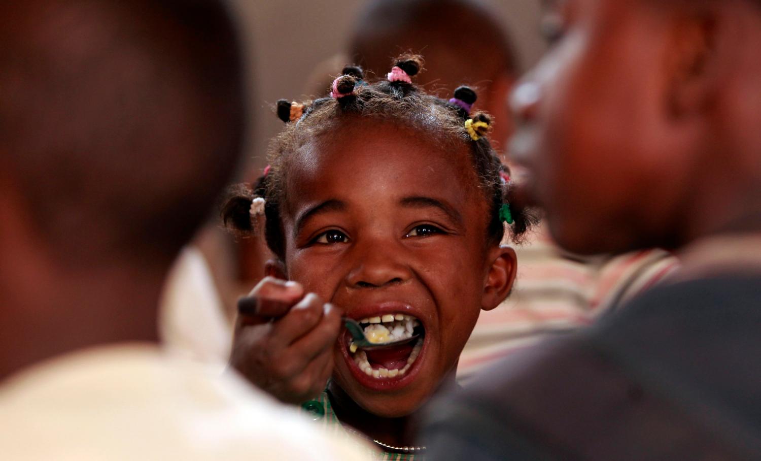 A Malagasy child eats at the United Nations World Food Program (WFP) school feeding initiative at the Saint de Paul community centre in Tanjombato, a southern suburb of the capital Antananarivo, October 28, 2013. The WFP, in collaboration with partners, provide food assistance to poor children to support their access to education. The centre receives about 927 children aged between 5 to 18 years old, whose parents earn around 2000 Madagascan Ariary ($1) a day. They also receive primary education, literacy tuition, scholastic adjustment, professional training and learn new crafts. REUTERS/Thomas Mukoya (MADAGASCAR - Tags: EDUCATION FOOD HEALTH SOCIETY POVERTY TPX IMAGES OF THE DAY)