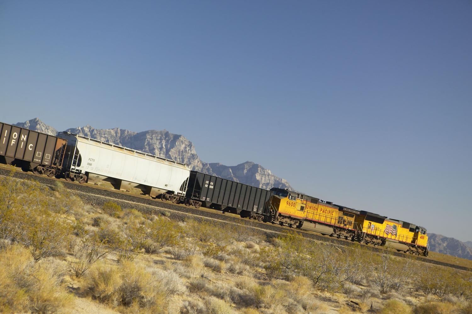 Freight train travels through desert and mountainous areas of Mojave Desert in Southern California