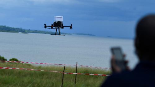 A man monitors a drone flying outdoors controlled by his cell phone.