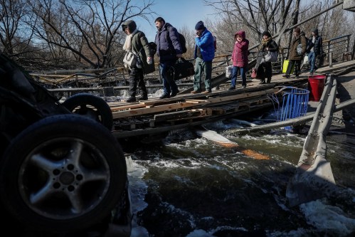 People cross the Irpin river near a destroyed bridge as they evacuate from Irpin town, amid Russia's invasion of Ukraine, outside of Kyiv, Ukraine March 12, 2022