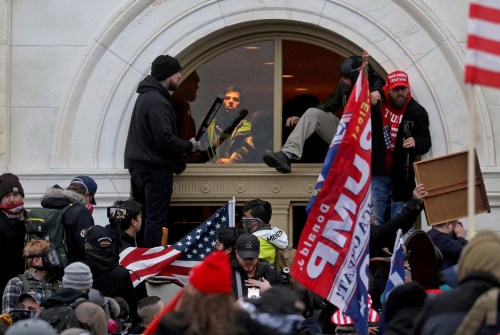 FILE PHOTO: A mob of supporters of then-U.S. President Donald Trump climb through a window they broke as they storm the U.S. Capitol Building in Washington, U.S., January 6, 2021.