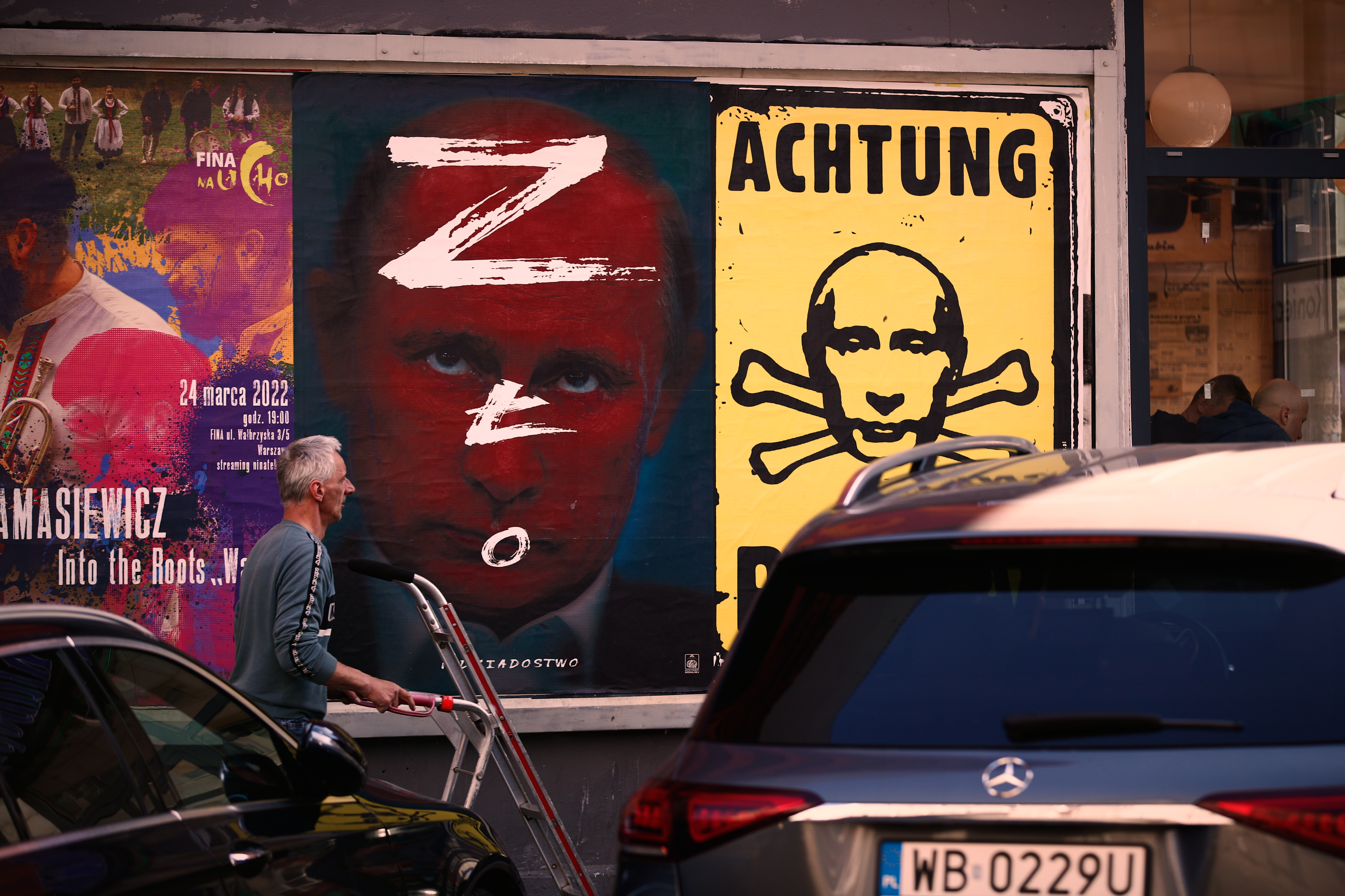 A man walks past a poster with an image of Russian president Vladimir Putin pained with the Russian Z sign used by the invading army and the word in Polish for 'evil' in Warsaw, Poland on 23 March, 2022. (Photo by STR/NurPhoto)NO USE FRANCE