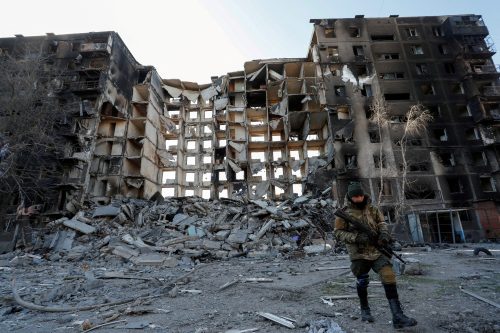 FILE PHOTO: A service member of pro-Russian troops walks near an apartment building destroyed in the course of Ukraine-Russia conflict in the besieged southern port city of Mariupol, Ukraine March 28, 2022. REUTERS/Alexander Ermochenko/File Photo