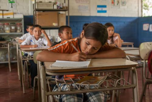 Young Colombian girl writing at a school desk.