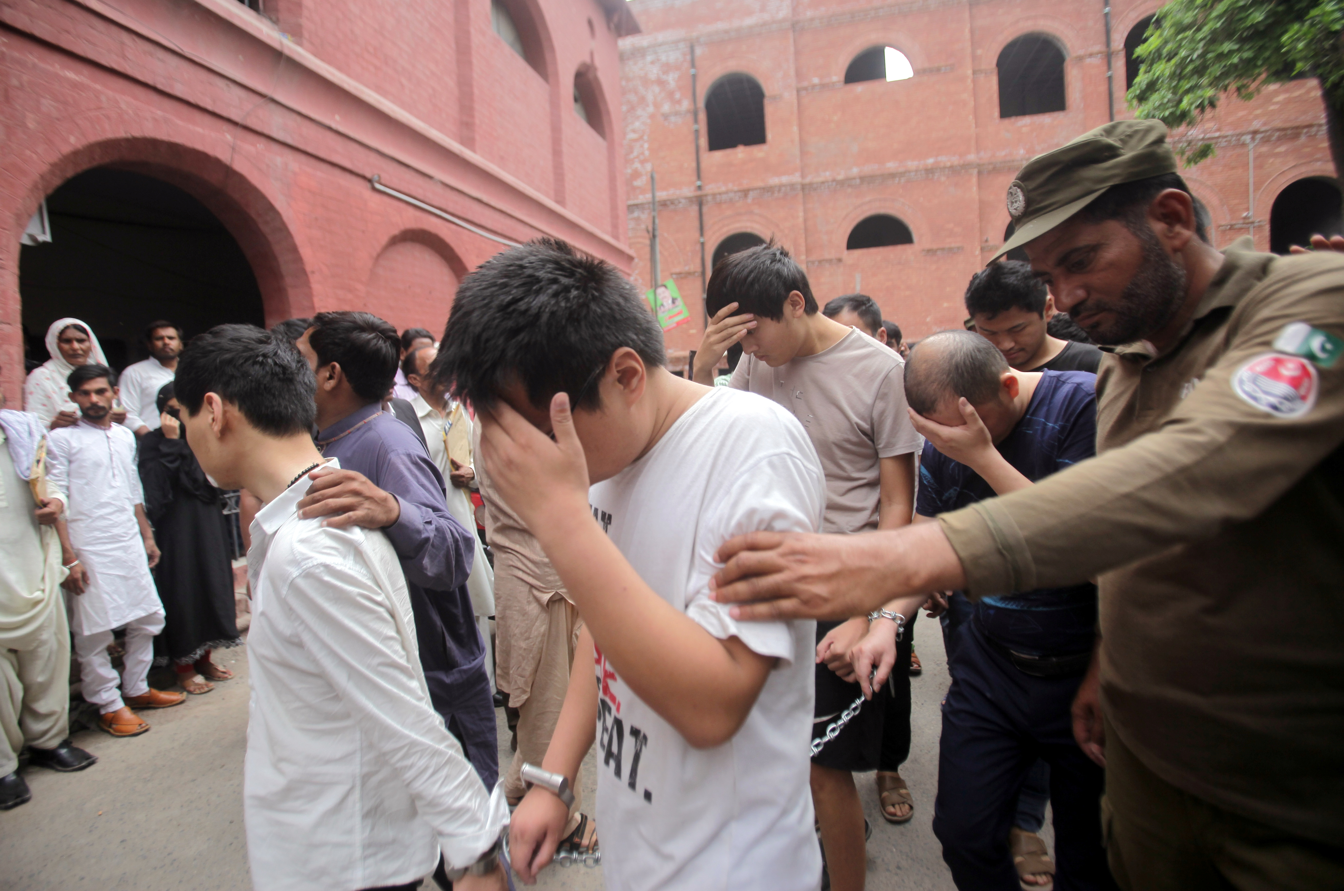 Chinese nationals, who, according to Pakistan Federal Investigation Agency (FIA), are suspected members of a prostitution ring, taking young Pakistani women to China, are escorted by police and officials during their civil court appreance in Lahore, Pakistan May 11, 2019. REUTERS/Mohsin Raza