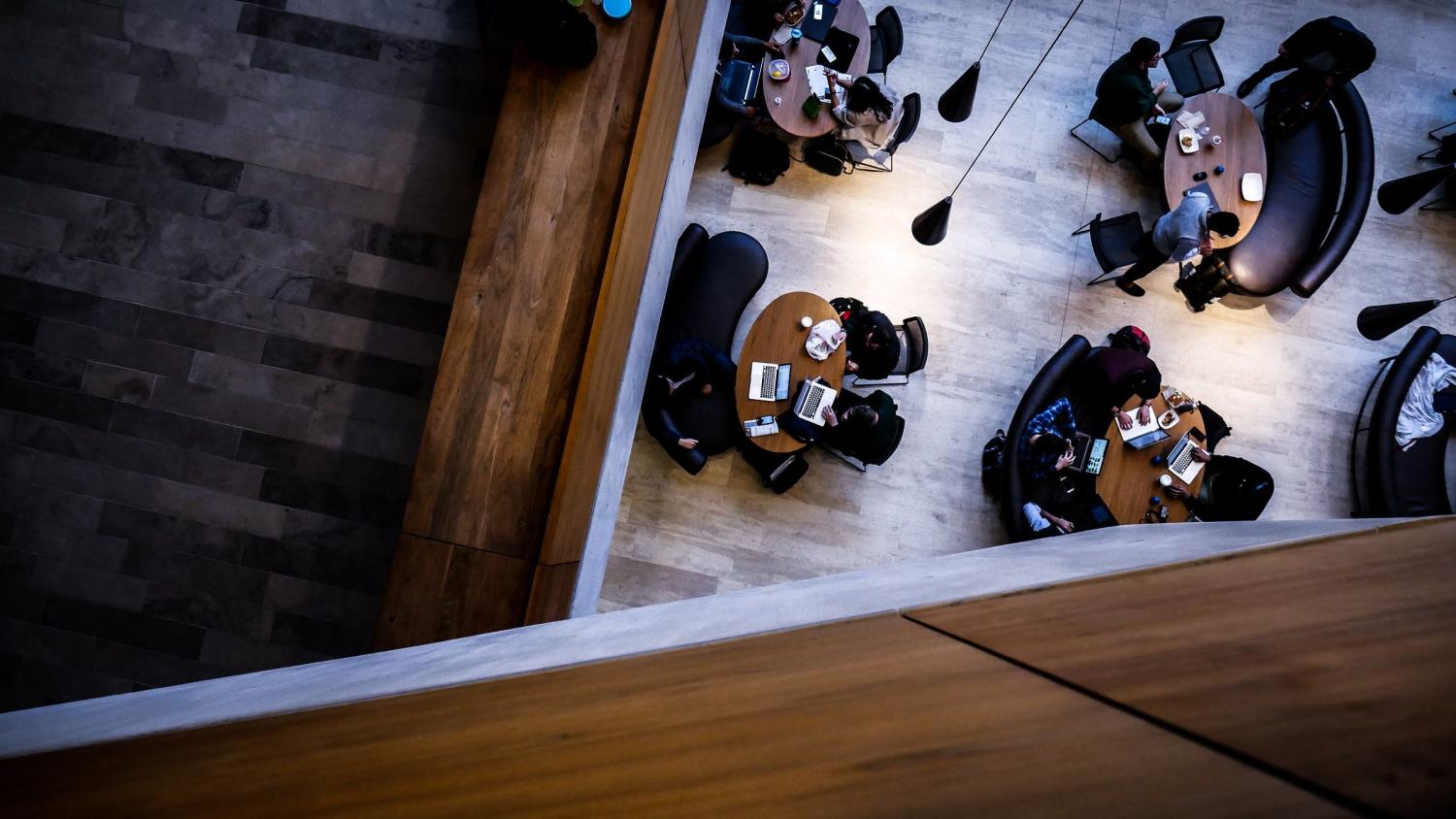 A top-down view of college students working in a common meeting space on campus.