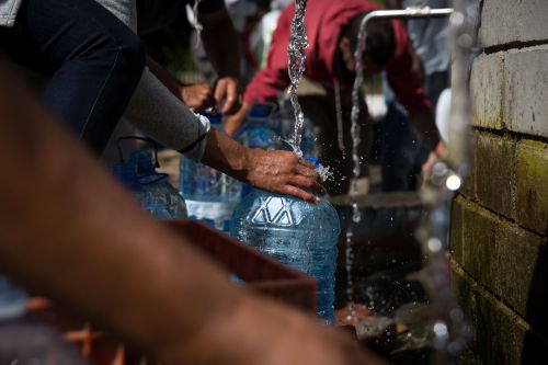 People collecting water in plastic bottles at natural water spring during drought at Newlands Cape Town South Africa.