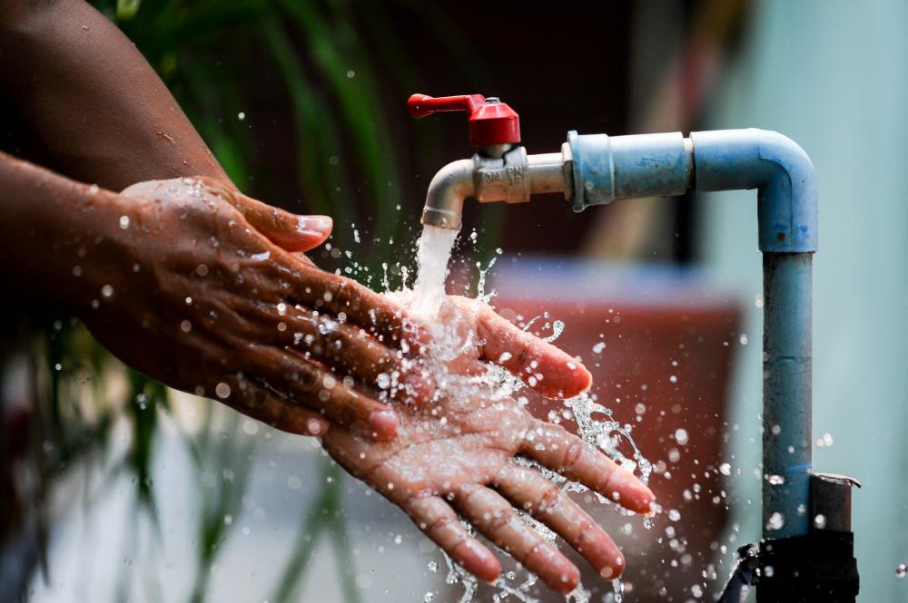 African woman washing hands under running water