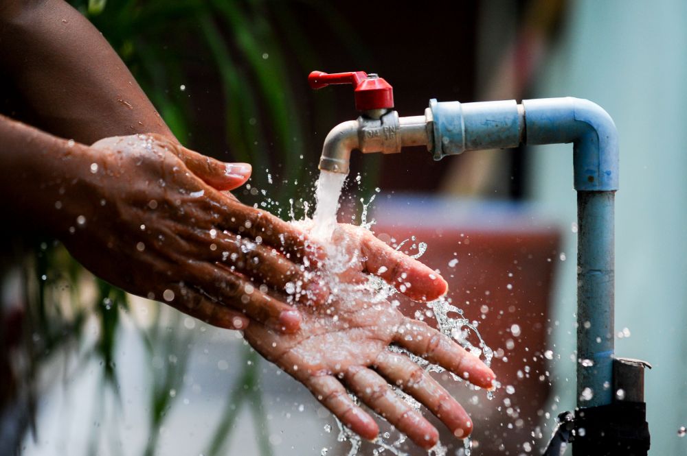 African woman washing hands under running water