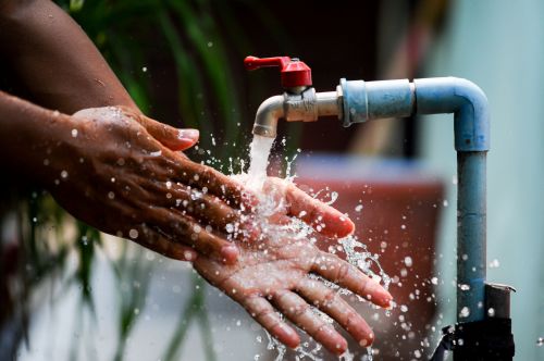 African woman washing hands under running water