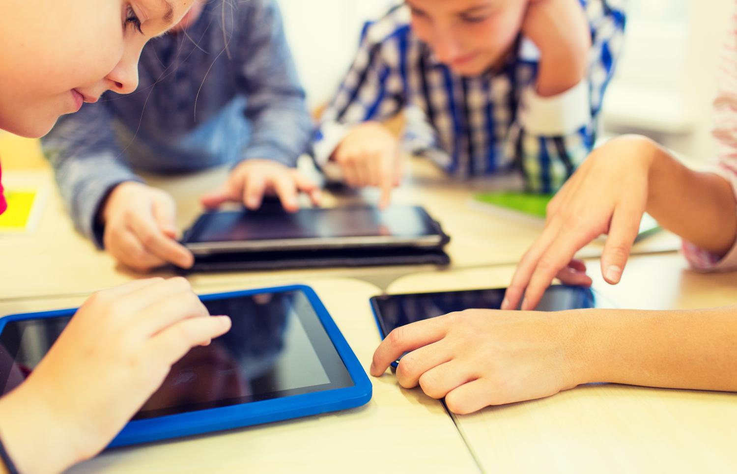 Close up of school kids with tablet computers in classroom.