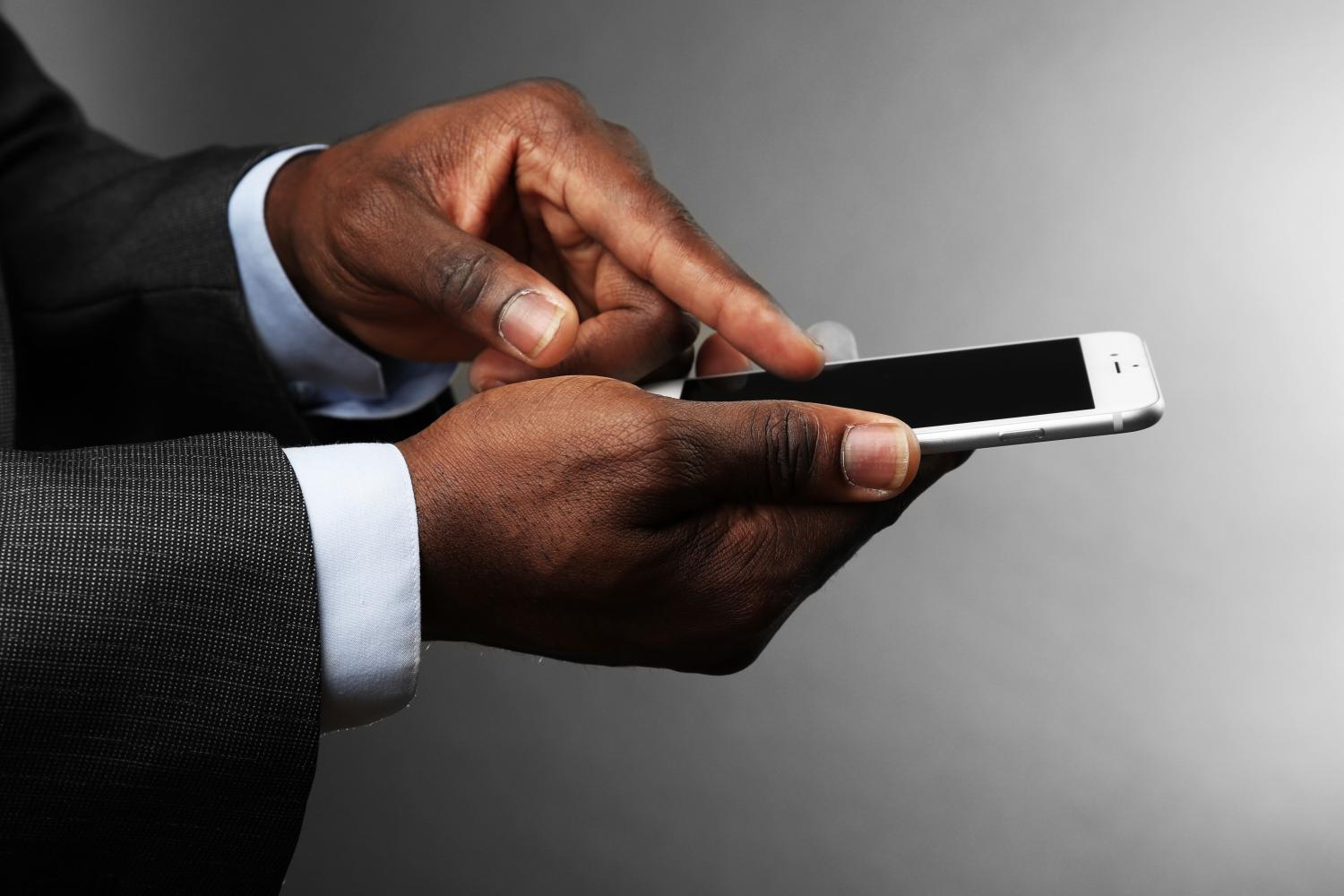 African man wearing a suit and holding a smartphone