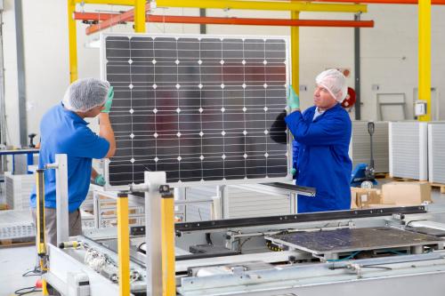 Factory workers lifting new solar panel from production line