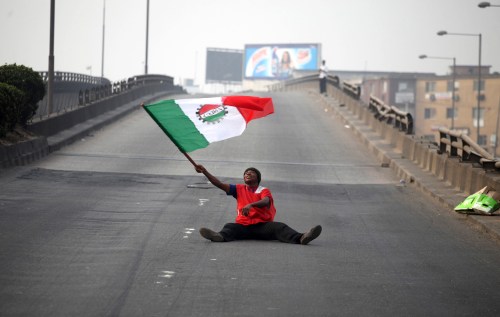 A protester waves a flag on an empty road during a protest against a fuel subsidy removal in Lagos January 9, 2012. Thousands of Nigerians took to the streets across Africa's top oil producing nation on Monday, launching an indefinite nationwide strike to protest against the axing of fuel subsidies.  REUTERS/Akintunde Akinleye (NIGERIA - Tags: CIVIL UNREST POLITICS ENERGY BUSINESS TPX IMAGES OF THE DAY)