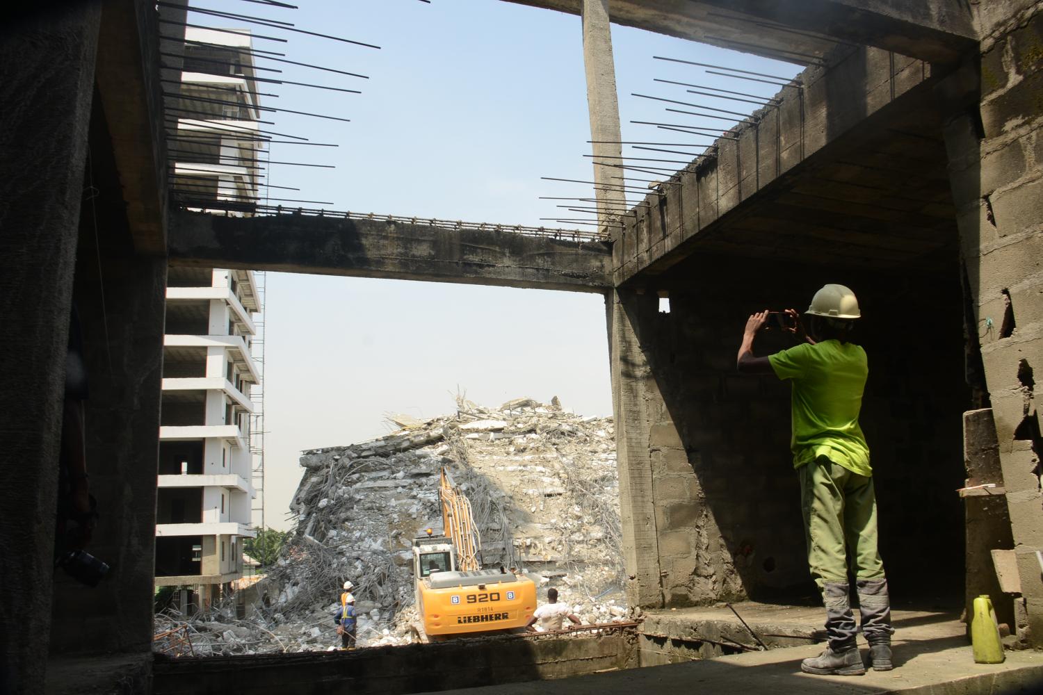 A site engineer stands to take picture across a building at the site of a collapsed building in Ikoyi district in Lagos, Nigeria, 02 November 2021. The Lagos State emergency rescue agency confirmed that No fewer than 21 people have been confirmed dead, while six of the nine survivors are currently undergoing treatment, three have been discharged in the 21-storey building that collapsed on Monday on Gerrard Road, in the Ikoyi area of Lagos State. (Photo by Olukayode Jaiyeola/NurPhoto)NO USE FRANCE