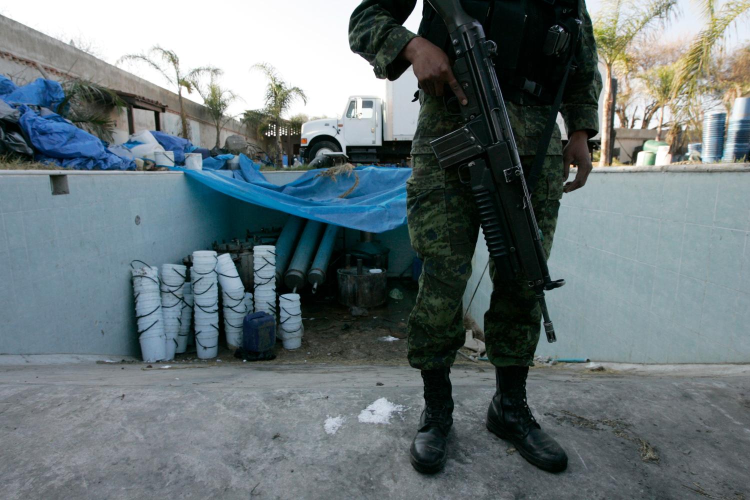 A soldier stands guard at an emptied swimming pool containing buckets at a clandestine drug processing laboratory discovered inside a ranch in Tlajomulco de Zuniga, on the outskirts of Guadalajara February 9, 2012. Soldiers found 15 tonnes of  the synthetic drug Methamphetamine, according to local media.  REUTERS/Alejandro Acosta (MEXICO - Tags: CRIME LAW CIVIL UNREST DRUGS SOCIETY)