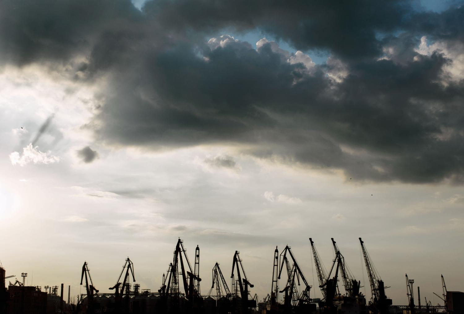 In the evening, the silhouette Industrial port cranes against the backdrop of storm clouds in Odessa, Ukraine