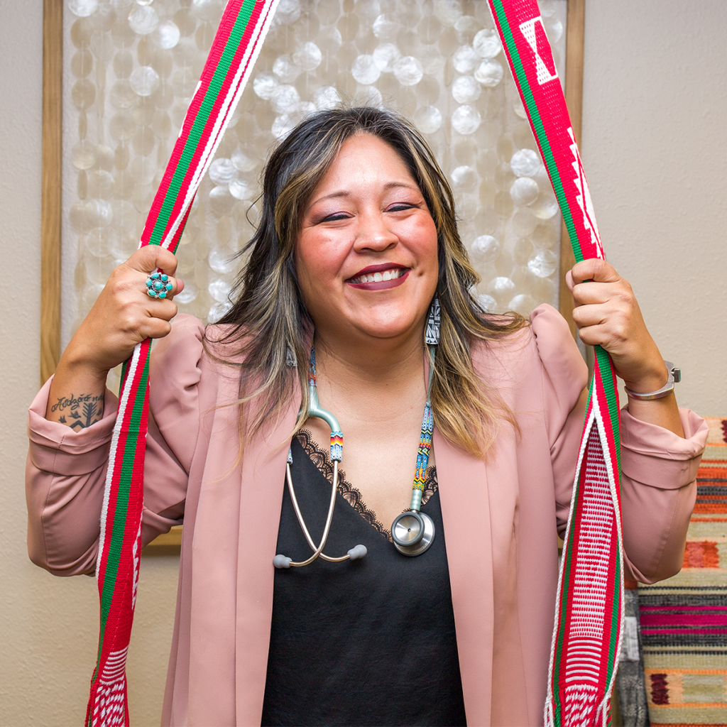 Nicolle L. Gonzales BSN, RN, MSN, CNM (Founder and Midwifery Director) holds onto a traditional red and white birthing belt.