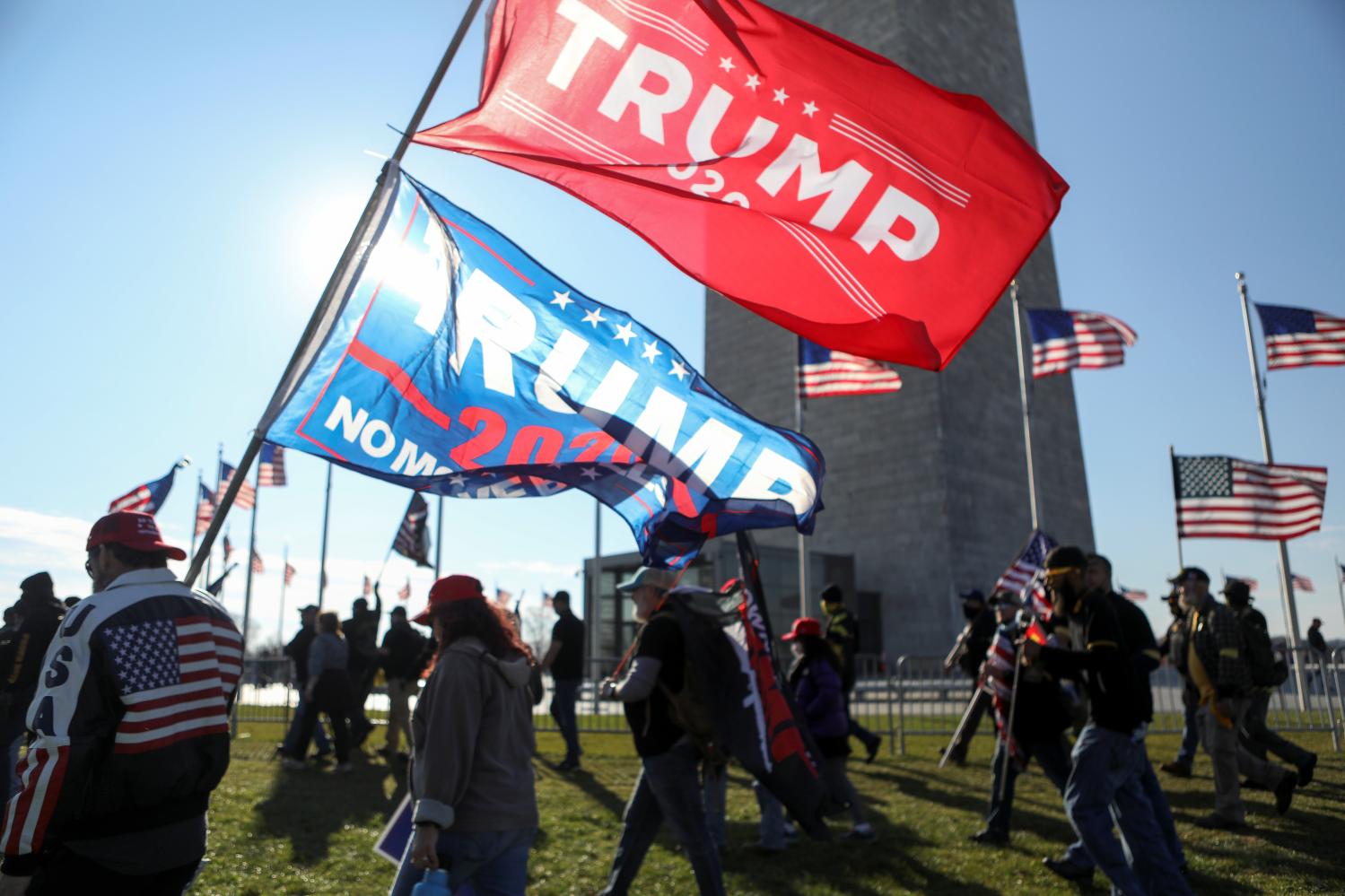 A man holds flags as supporters of U.S. President Donald Trump along with members of the far-right group Proud Boys walk past a Washington Monument during a rally to protest the results of the election, in Washington, U.S., December 12, 2020. REUTERS/Jim Urquhart