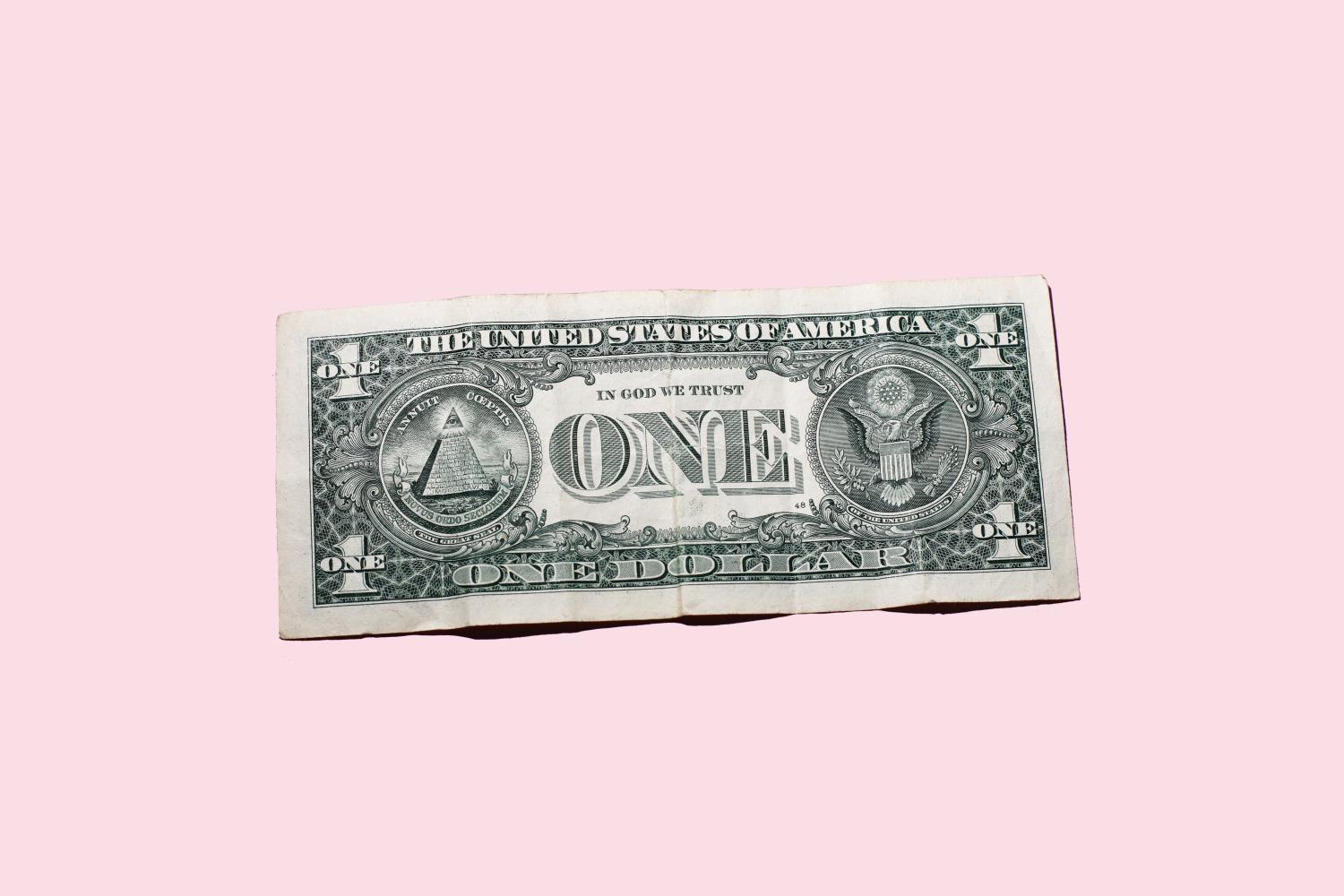 a single US dollar bill, back side up, against a pink background