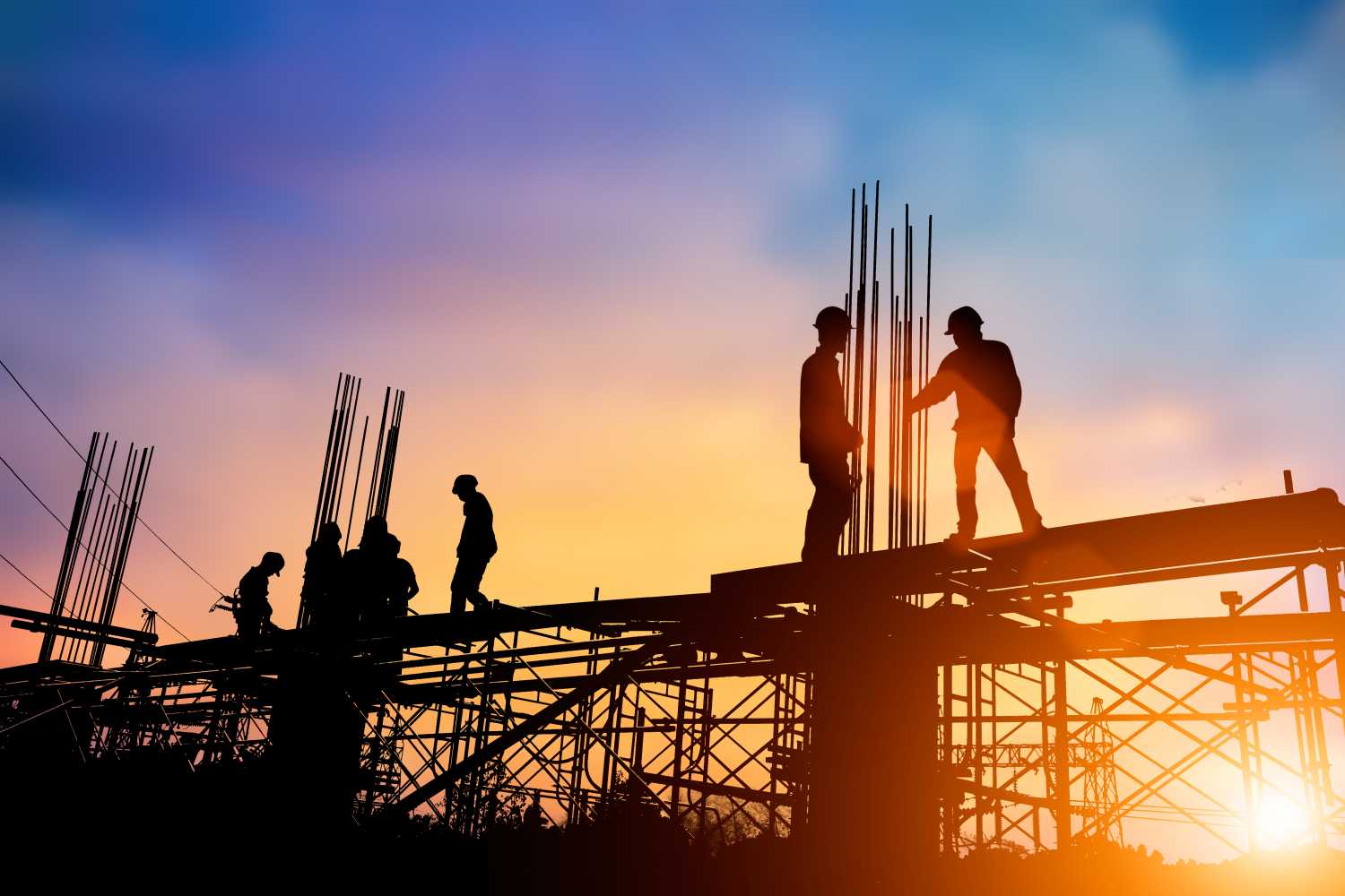 Silhouette of standing construction crew on worksite at sunrise