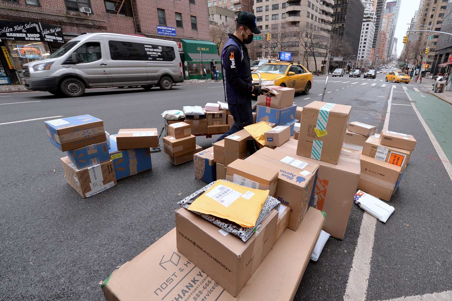 Sprawled out on Second Avenue behind his truck, a FEDEX worker sorts out packages to be delivered on Christmas Eve, New York, NY, December 24, 2020. With a resurgence in COVID-19 infections, package shipping services such as FEDEX, UPS and the USPS are expecting to deliver a record number of packages for 2020. (Photo by Anthony Behar/Sipa USA)No Use UK. No Use Germany.