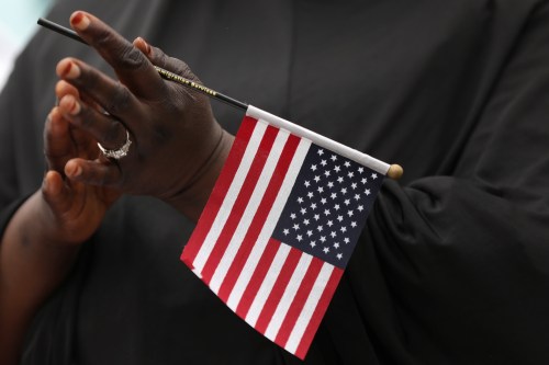 Fatoumata Jangana, from Gambia, claps holding an American flag during a naturalization ceremony at Franklin D. Roosevelt Four Freedoms Park, Roosevelt Island in New York City, U.S., June 16, 2017.  REUTERS/Shannon Stapleton