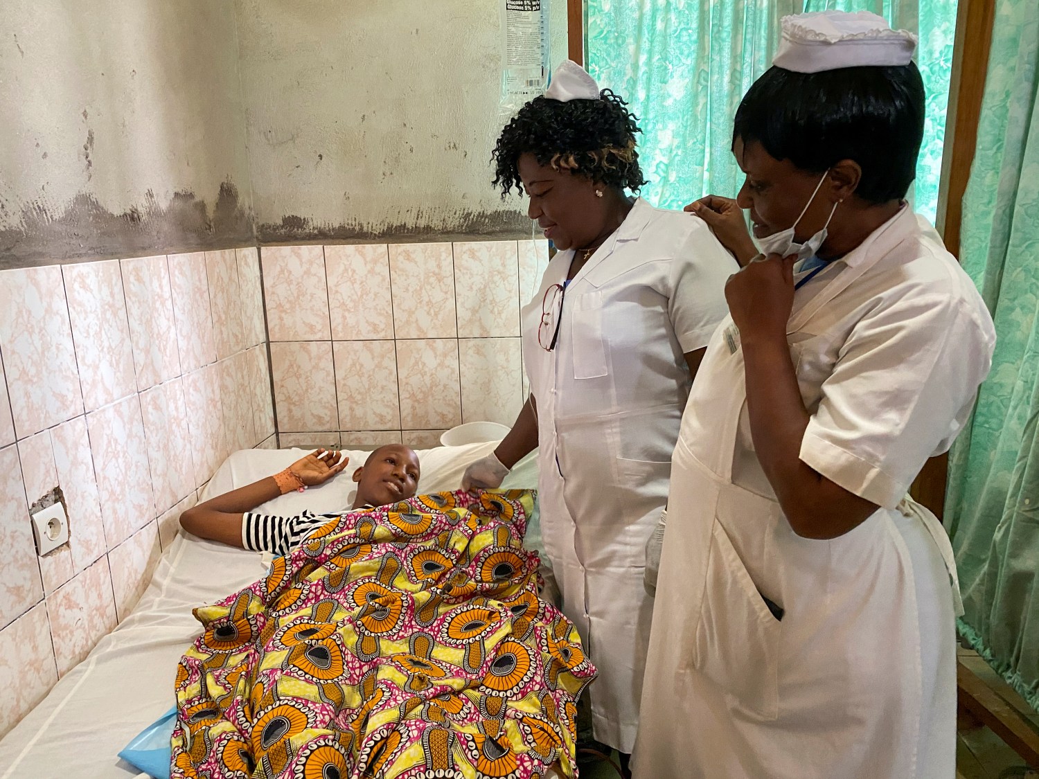 Nurses talk with Blessing Mbeng, 13, who was shot by gunmen after they stormed his school, as he lies in a hospital bed in Kumba, Cameroon October 25, 2020. REUTERS/Josiane Kouagheu