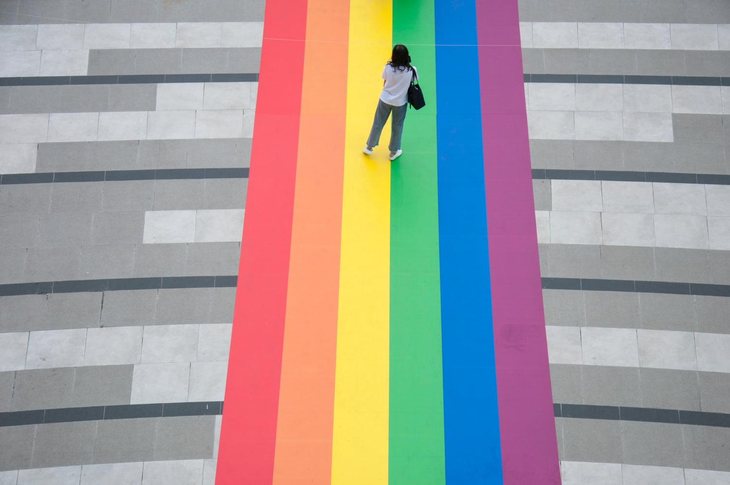 A woman stand on a huge rainbow flag placed at the entrance of Samyan Mitrtown shopping mall.Samyan Mitrtown, a mixed-use shopping, office, residential and leisure development celebrated the LGBTQ Pride Month 2021 by decorated the floor at the entrance and the tunnel of the mall with the huge and long rainbow flag. "Samyan Mitr Proud 100% Love" in Bangkok, Thailand. (Photo by Peerapon Boonyakiat / SOPA Images/Sipa USA)No Use Germany.