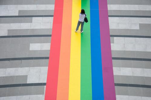 A woman stand on a huge rainbow flag placed at the entrance of Samyan Mitrtown shopping mall.Samyan Mitrtown, a mixed-use shopping, office, residential and leisure development celebrated the LGBTQ Pride Month 2021 by decorated the floor at the entrance and the tunnel of the mall with the huge and long rainbow flag. "Samyan Mitr Proud 100% Love" in Bangkok, Thailand. (Photo by Peerapon Boonyakiat / SOPA Images/Sipa USA)No Use Germany.