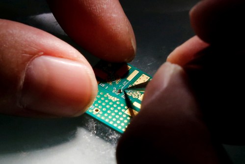 FILE PHOTO: A researcher plants a semiconductor on an interface board during a research work to design and develop a semiconductor product at Tsinghua Unigroup research centre in Beijing, China, February 29, 2016. REUTERS/Kim Kyung-Hoon/File Photo