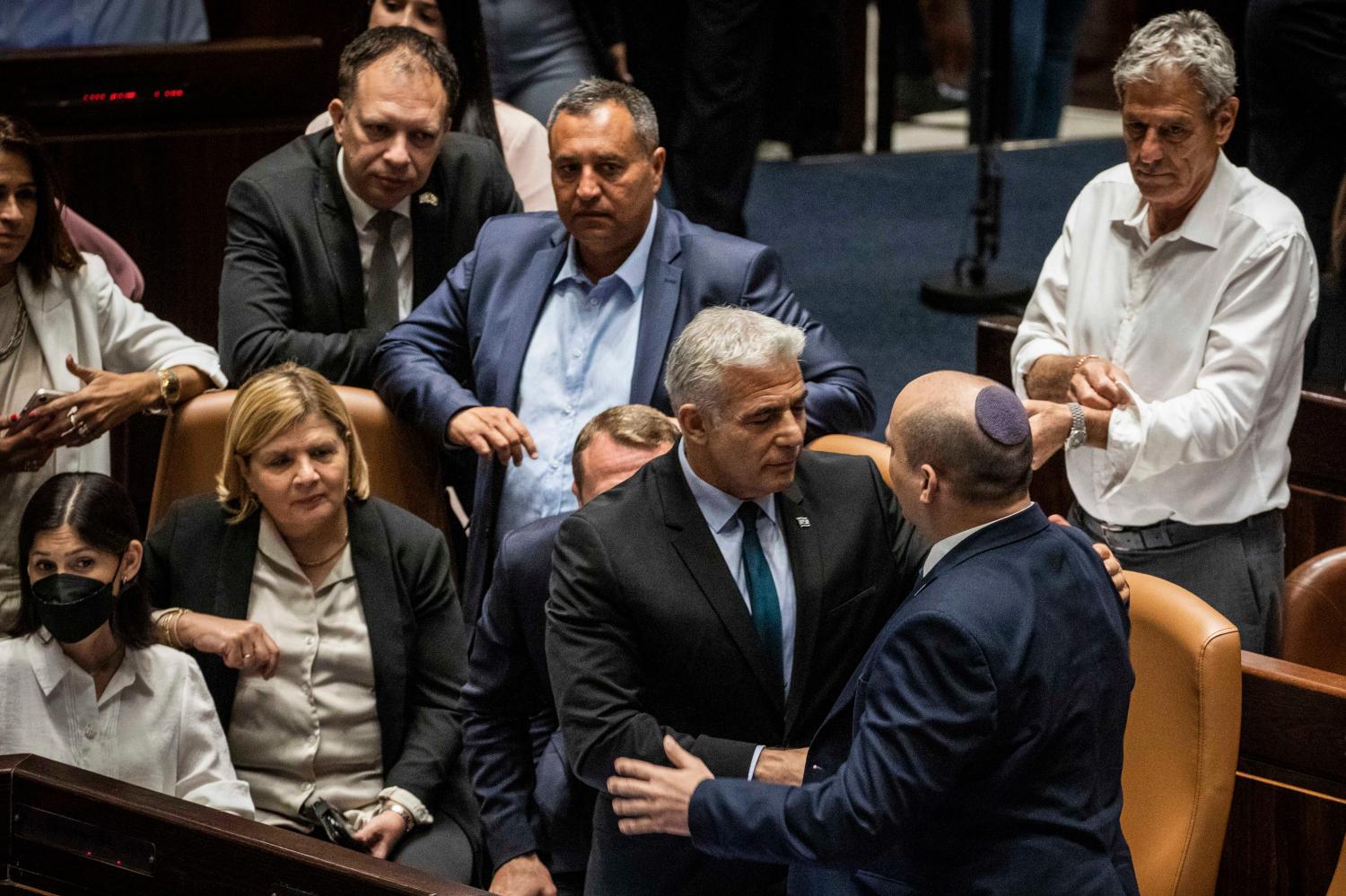 Foreign Affairs Minister of Israel Yair Lapid (C) and Israeli Prime minister Naftali Bennet (2nd R) shake hands following the government dissolving vote session at the Israeli Knesset. Yair Lapid is to take over from Bennett as head of government until a new government is in office. Ilia Yefimovich/dpa