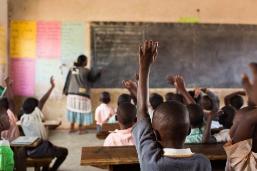 students raising hands in classroom