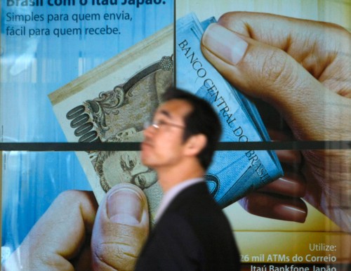 A man walks past a poster of a bank at a business district in Tokyo March 16, 2009. The Bank of Japan is considering purchasing subordinated debt issued by banks to help bolster their capital, the Nikkei business daily said on Monday, in a move to contain the fallout from the global financial crisis.    REUTERS/Kim Kyung-Hoon (JAPAN BUSINESS)