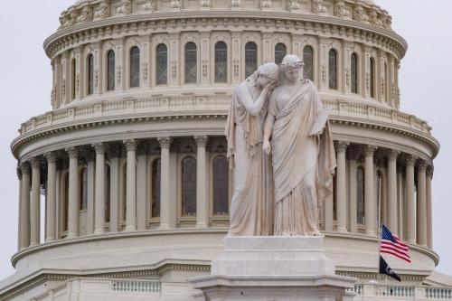 Seen behind weeping figures of the Peace Monument, flags are flown at halfstaff on the U.S. Capitol building on January 6, 2022, the one year anniversary of the insurrection at the Capitol building (Photo by Bryan Olin Dozier/NurPhoto)NO USE FRANCE