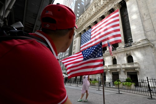 People walk past the facade of the New York Stock Exchange draped in a large American Flag, New York, NY, July 6, 2022. Stocks made modest gains as investors read over reports by the Federal Reserve to see if interest rates could go up to fight inflation as a fear of a recession looms over the U.S. economy.