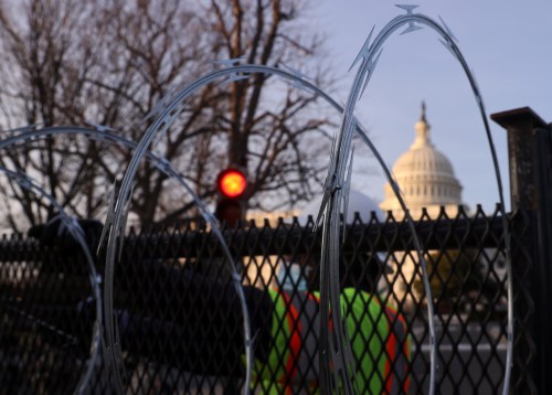 Workers install razor wire atop the unscalable fence surrounding the U.S. Capitol in the wake of the January 6th riot and ahead of the upcoming inauguration in Washington, U.S. January 14, 2021. REUTERS/Jonathan Ernst