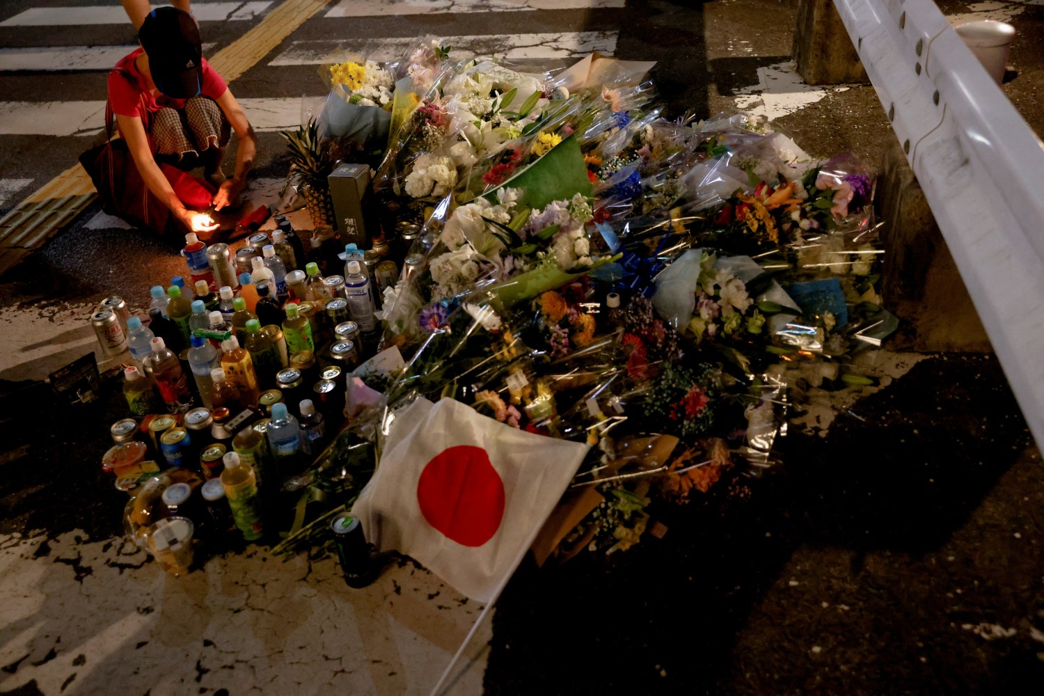 A person pays respects next to tributes laid at the site where late former Japanese Prime Minister Shinzo Abe was shot while campaigning for a parliamentary election, near Yamato-Saidaiji station in Nara, western Japan, July 8, 2022. REUTERS/Issei Kato