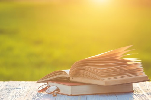 stock image of books stacked ontop of one another with sunlight in background