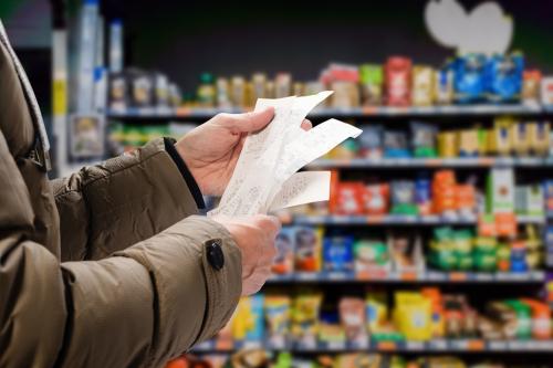 man looking at grocery store receipt in grocery aisle