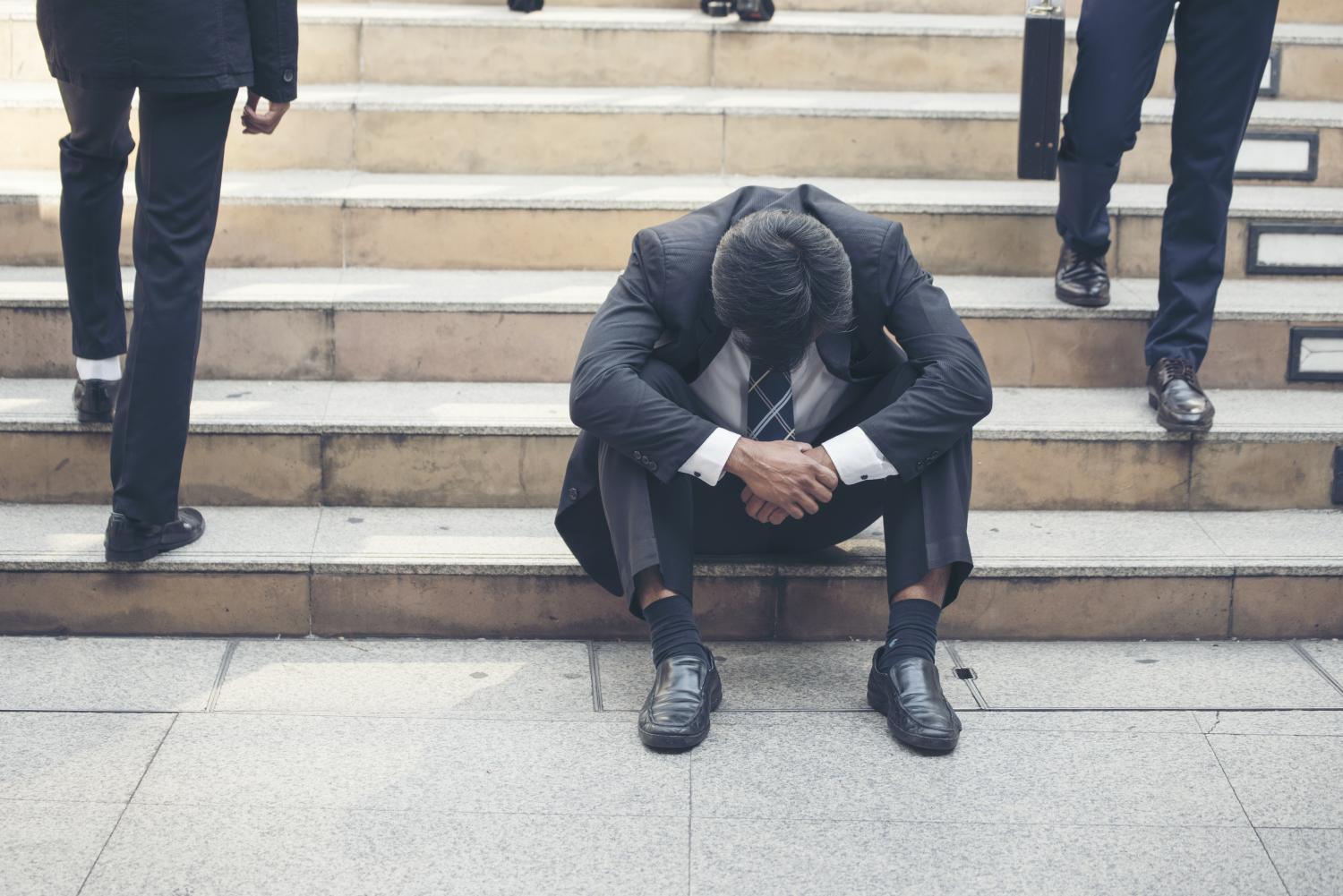 Man sitting on steps while others pass by