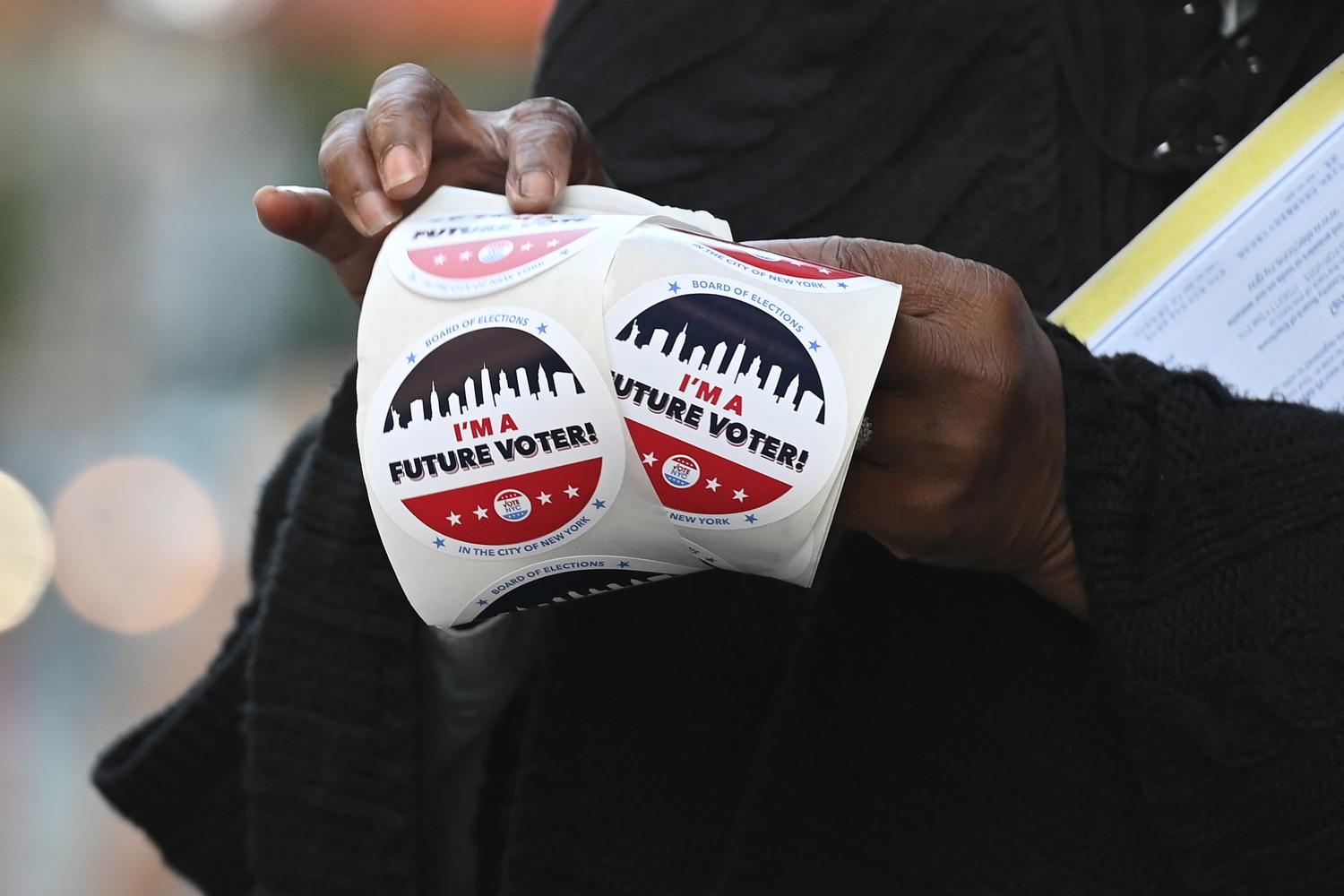 Donna Hawkins, a clerk for the registration department of the Board of Elections hands out future voter stickers to people after theyve registered to vote outside the Board of Elections Manhattan borough office, in New York, NY, October 8, 2020. (Anthony Behar/Sipa USA)No Use UK. No Use Germany.